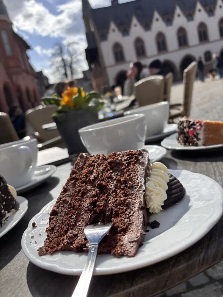 Schokoladentorte und Kaffee auf dem Marktplatz in Goslar, im Hintergrund das Rathaus