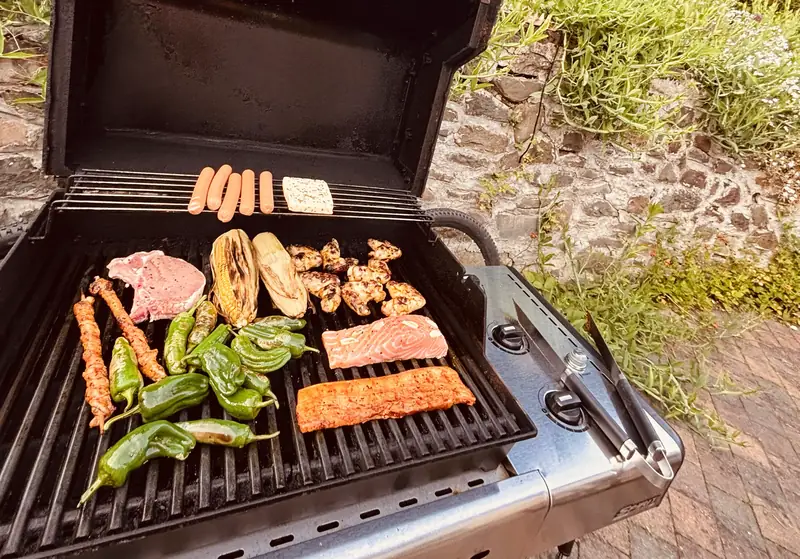 Grillen im Innenhof – Gasgrill mit Gemüse, Fleisch und Würstchen