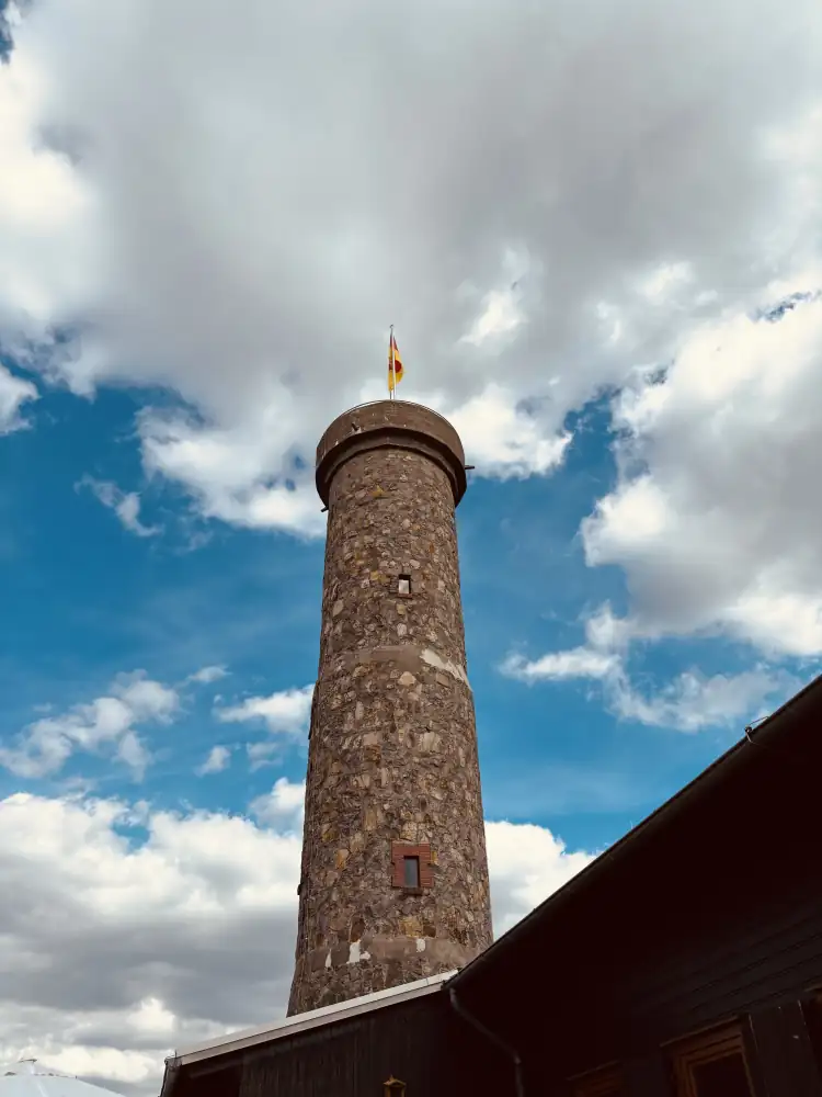 Der steinerne Knollenturm von unten gesehen, mit Fahne auf der Spitze