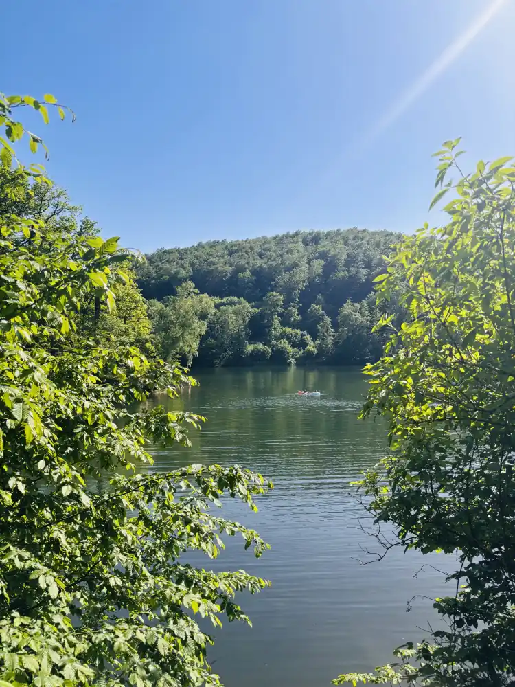 Wiesenbeker Teich durch Buchenlaub gesehen, auf dem Wasser ein Schlauchboot
